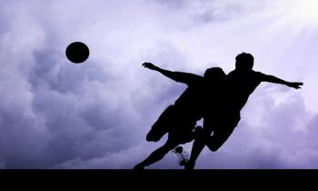 Silhouettes of footballers on a cloudy sky